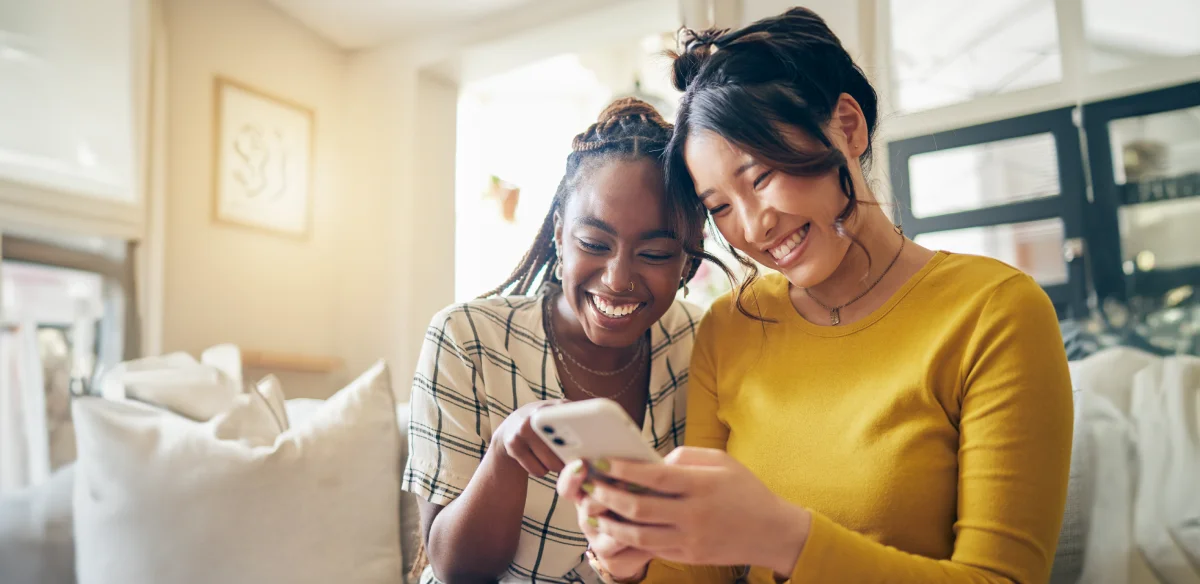Two students looking at their phone and smiling